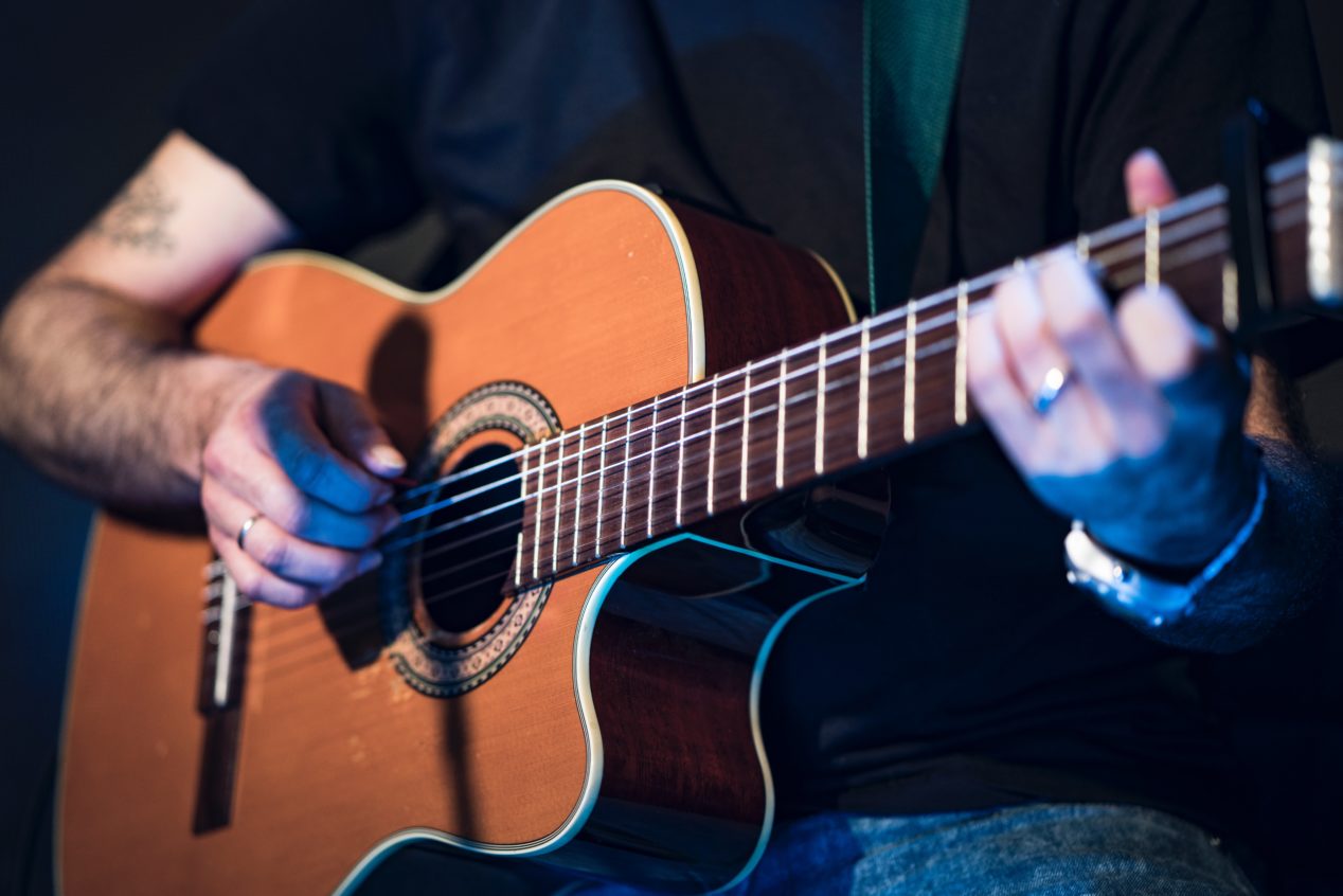 Photo of a person playing the guitar with their fingers.