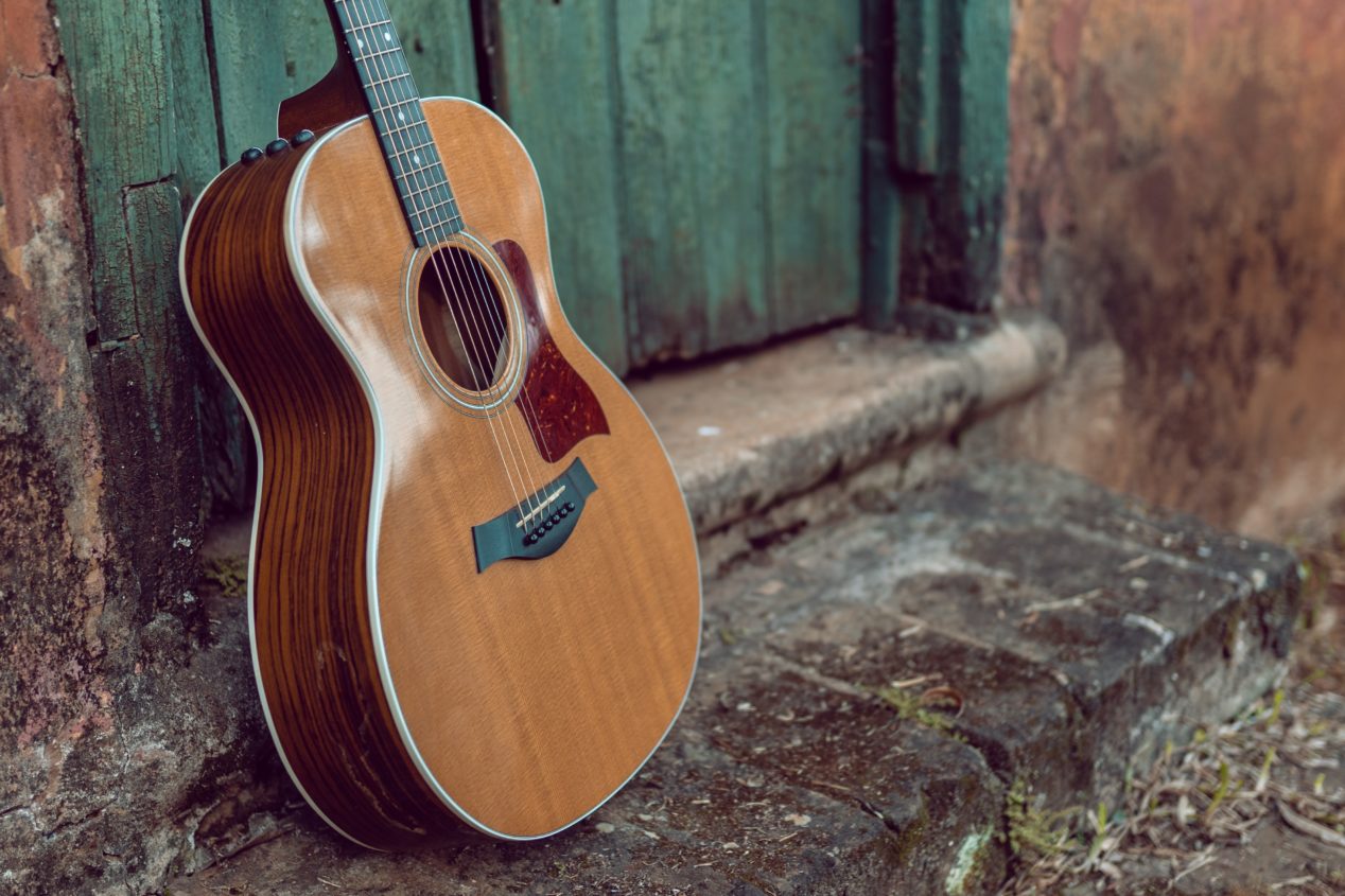 Photo of an acoustic guitar sitting outside of a door.