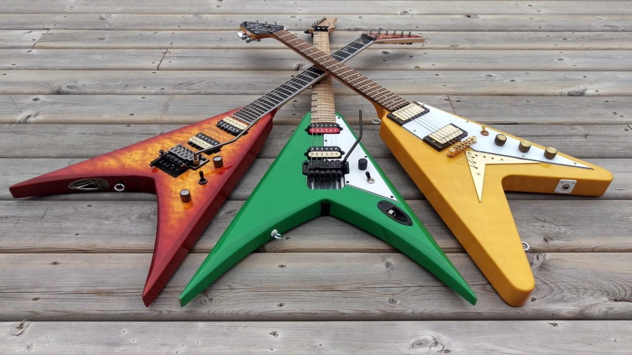 Photo of three flying V guitars on a wooden porch.