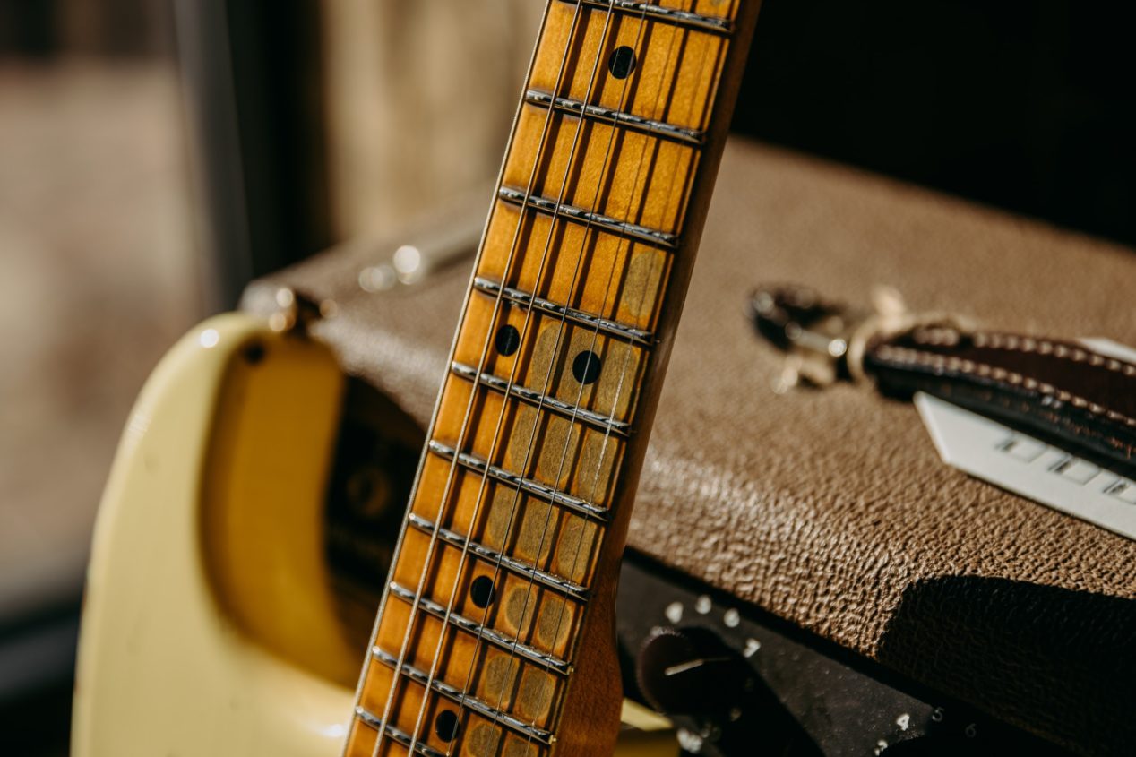 Close up photo of a maple necked Stratocaster, focusing on the 12th fret area.
