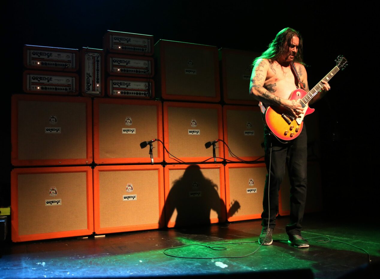 Matt Pike playing in front of a wall of Orange amps